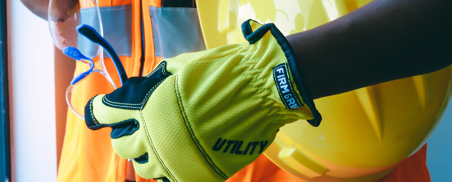 Worker wearing safety gloves and holding a hard hat